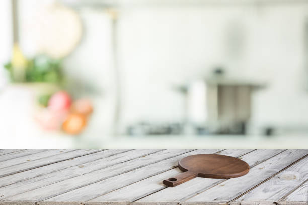 istock Blurred and abstract kitchen background. Empty wooden tabletop with cutting board  and defocused modern kitchen for display or montage your products. 811420724