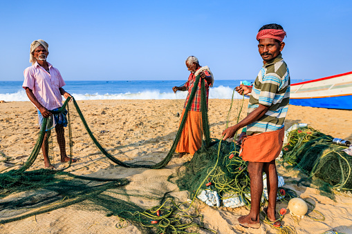 Indian fishermen at work. Fishermen are checking and repairing fishing net, Kerala, India.