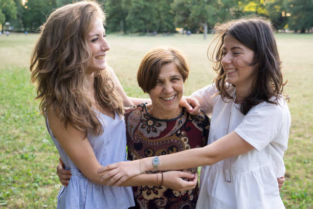 istock Mother and daughters embracing in a park 811434060