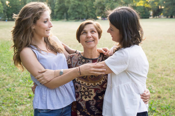 istock Mother and daughters embracing in a park 811434132