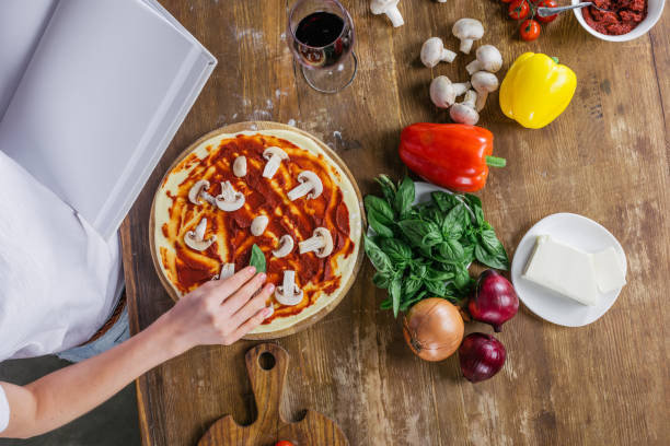 istock Top view of woman holding blank cookbook while preparing pizza at kitchen 811434266