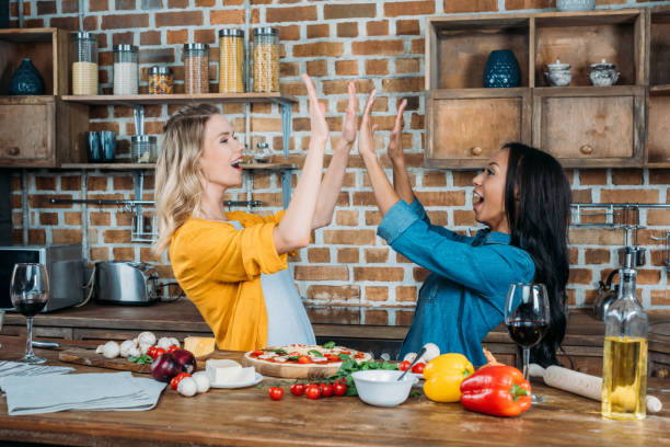 istock Cheerful young miltiehnic women giving high five while cooking in kitchen 811436614