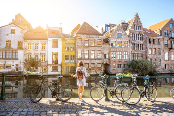 Woman traveling in Gent old town, Belgium Sunrise view on the water channel with beautiful old buildings with woman standing near the bicycles in Gent city belgium stock pictures, royalty-free photos & images