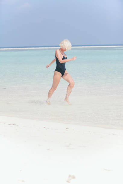 istock Woman in bikini running through water on sandy beach, Maldives 811448328