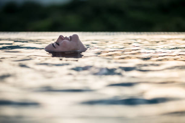 Happy woman lying in the pool and smiling while enjoying the water - lifestyle concepts