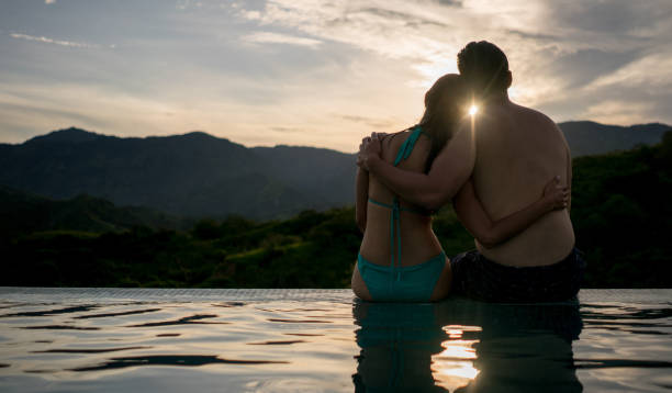 istock Romantic couple watching the sunset by the pool 811454032