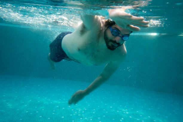 istock Latin American man swimming in the pool 811454040
