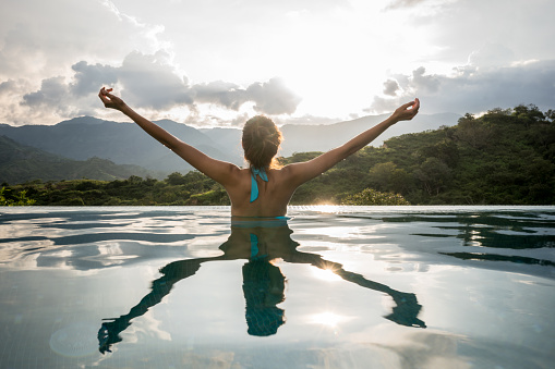 Woman relaxing in the pool and looking very happy with arms up - lifestyle concepts