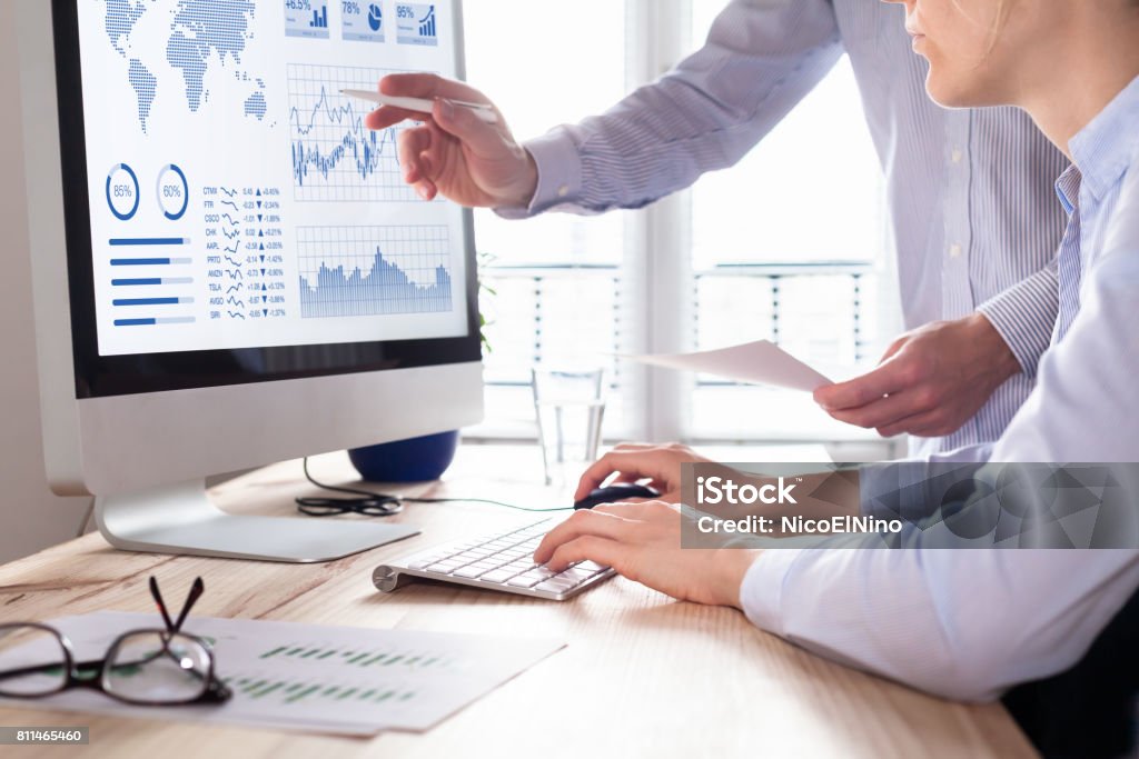 Two people analyzing stock market investment strategy on computer Two people analyzing stock market investment strategy with key performance indicator on financial dashboard and business intelligence on computer Computer Monitor Stock Photo