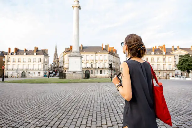 Young woman tourist enjoying beautiful view on the Marechal-Foch square with Loise column in Nantes city in France