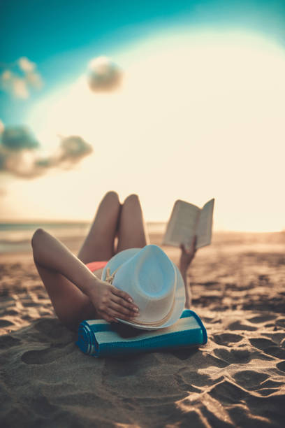 istock Female Reading and Enjoying Sunset on Beach by the Ocean 811467906