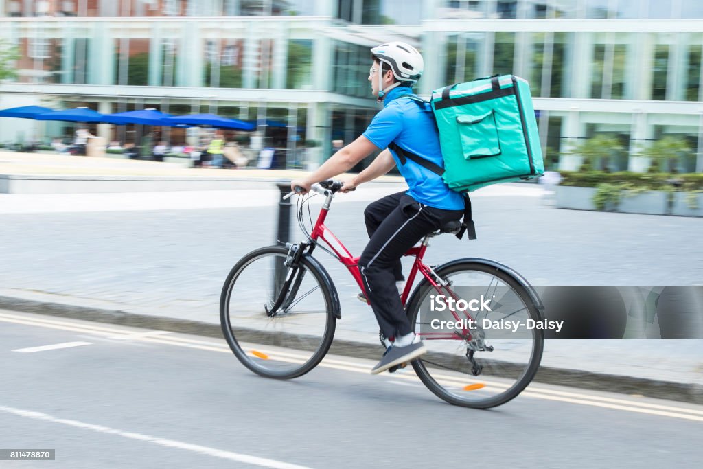 Courier On Bicycle Delivering Food In City Delivery Person Stock Photo