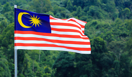Detail of the Malaysia national flag waving in the wind. Malaysia is a federal state in Southeast Asia. Rippled fabric. Textured background. Realistic 3d illustration. Close-up. Selective focus