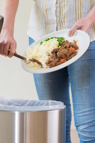 istock Woman Scraping Food Leftovers Into Garbage Bin 811497498