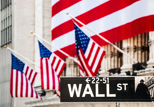 Wall Street Sign with New York Stock Exchange Building Out Of Focus In The Background