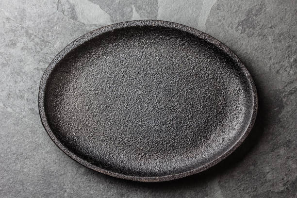 istock Food cooking background. Empty cast iron black plate on slate background 811505936