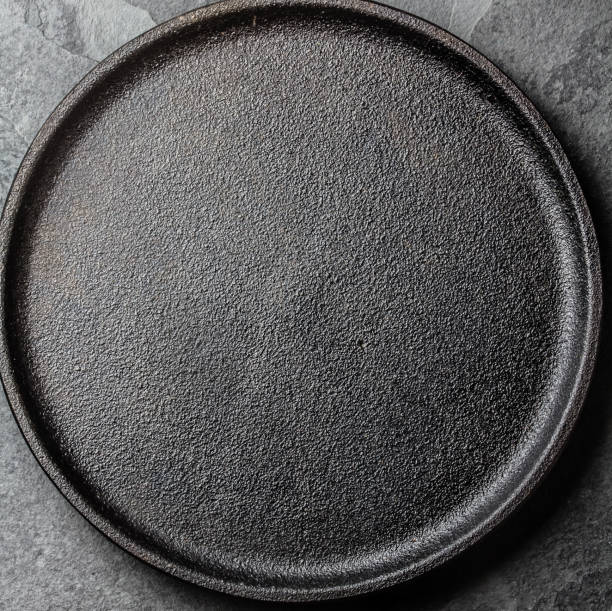 istock Food cooking background. Empty cast iron black plate on slate background 811505950