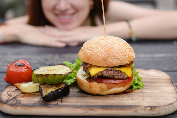 istock Cheeseburger on the wooden table, smiling face. 811540470