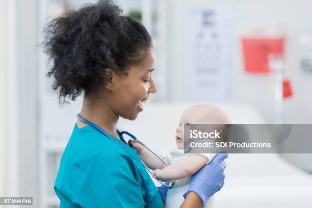 Adorable Baby Girl Looks At Caring Nurse Stock Photo - Download Image Now - Baby - Human Age, Nurse, Holding