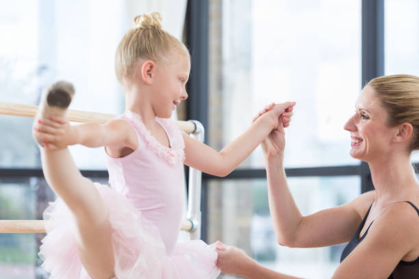 istock Ballet instructor helps young girl in class 811544902
