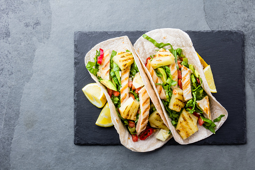 Mexican chicken tacos with grilled pineapple and vegetables on slate gray background