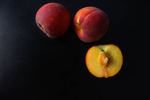 istock Peaches are whole and sliced on a black background. Empty space for text. 811555454