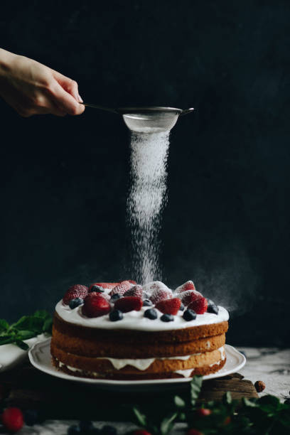 woman sifting sugar powder over cake - sifting imagens e fotografias de stock