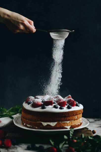 istock Woman sifting sugar powder over cake 811563172