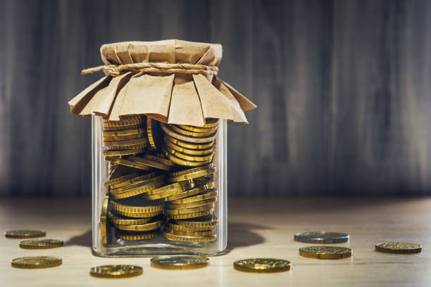 istock Euro coins in glass container over wooden background 811579746