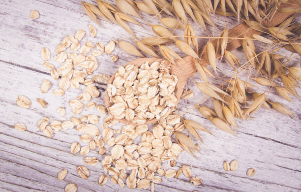 istock Raw oat flakes on a wooden table - closeup. 811580300