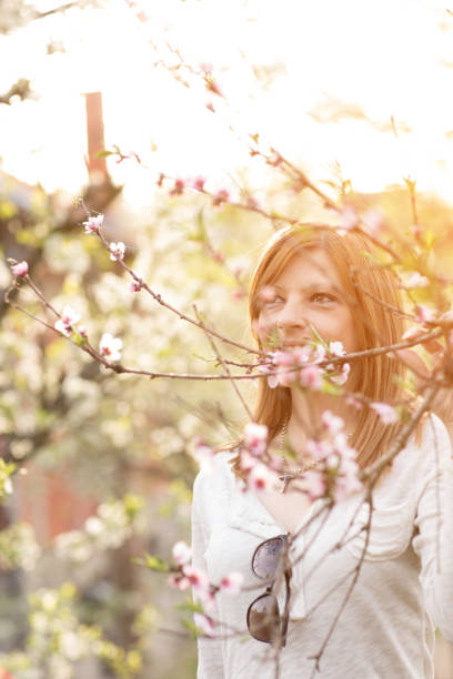 istock happy young woman under blossoming tree at sunny spring day 811585126