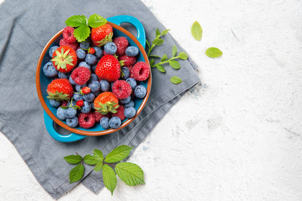 istock Mix of fresh berries on a plate on stone background, top view 811610296