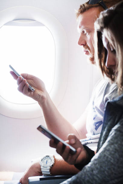 istock Couple holding a smartphone while seated by an airplane window 811628416