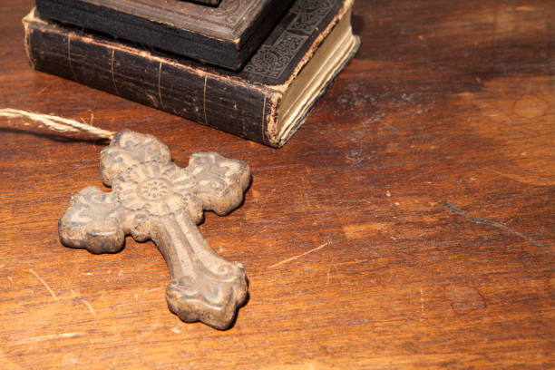 Cross with antique books on a wooden desk stock photo