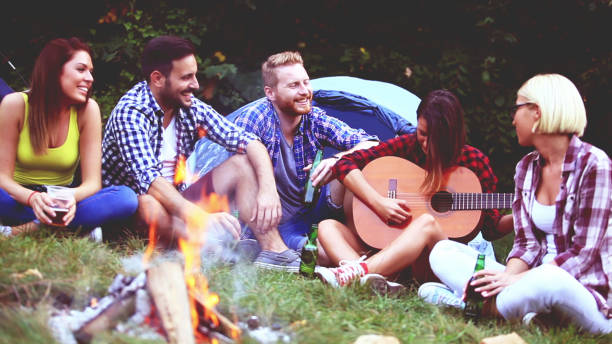 istock Five friends sitting next to campfire and singing song 811681928