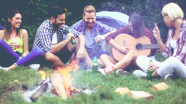 istock Five friends sitting next to campfire and singing song 811682082