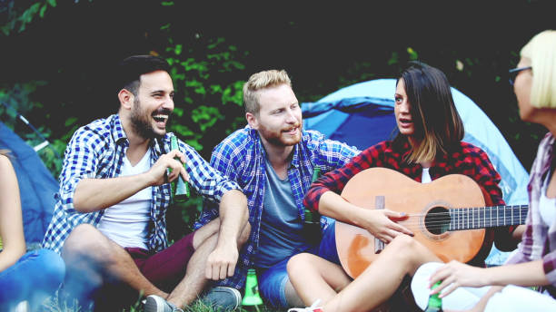 istock Four friends sitting next to campfire and singing song 811682106