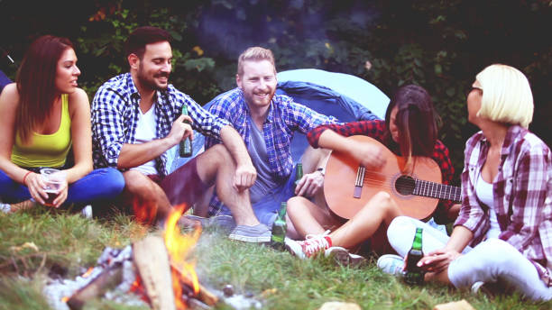 istock Five friends sitting next to campfire and singing song 811682360