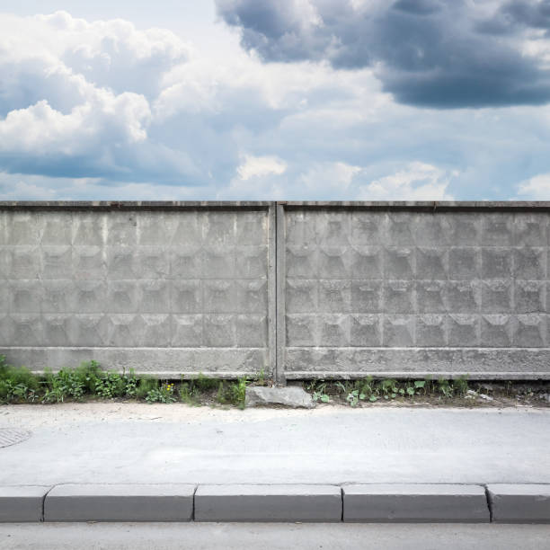 istock Old gray concrete fence under cloudy sky 811687692