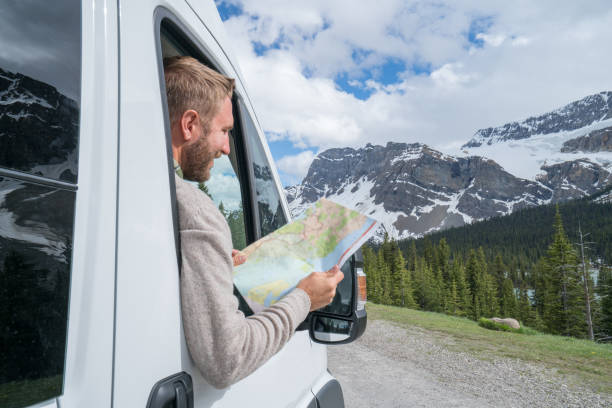 istock Young man looks at road map near mountain lake 811699190