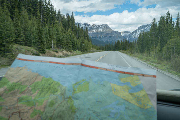 View of map inside vehicle, mountain road Point of view of mountain road, map on foreground. road map of canada stock pictures, royalty-free photos & images