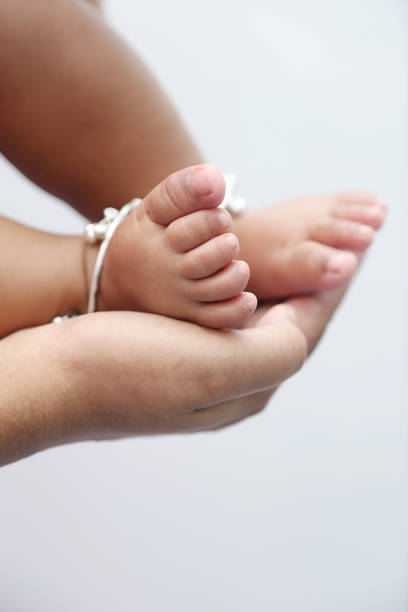 Mother holds baby feet in hands, isolated on white background.