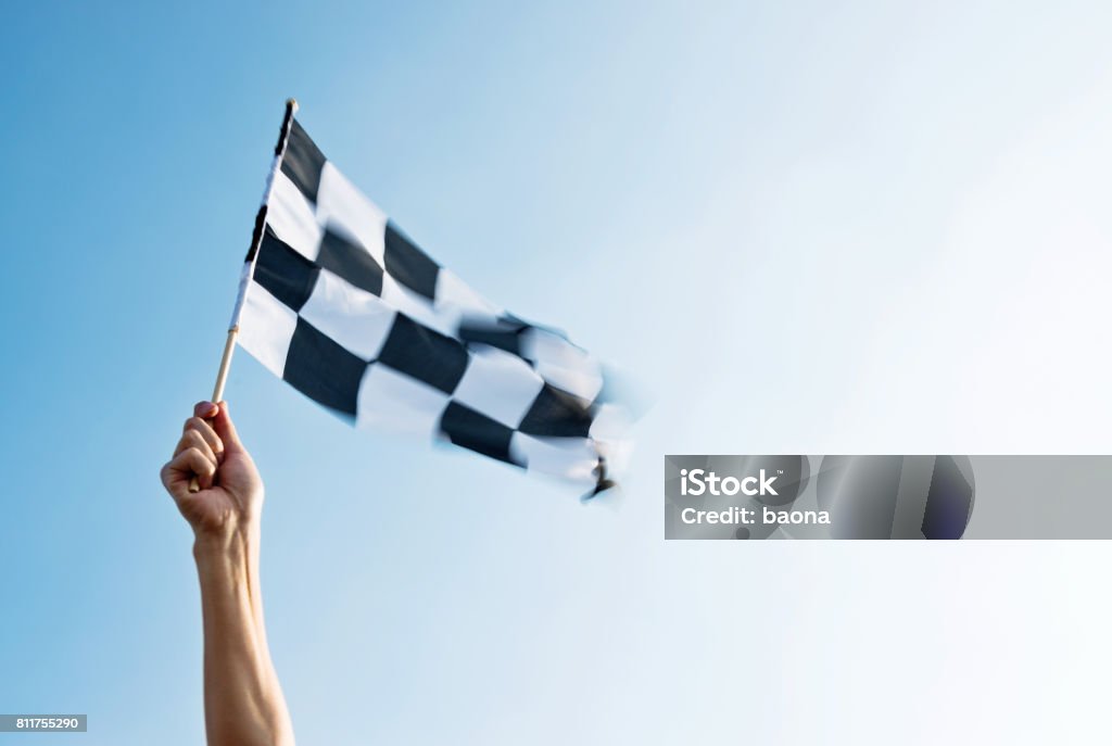 Man hand holding checkered flag in the wind Finish Line Stock Photo