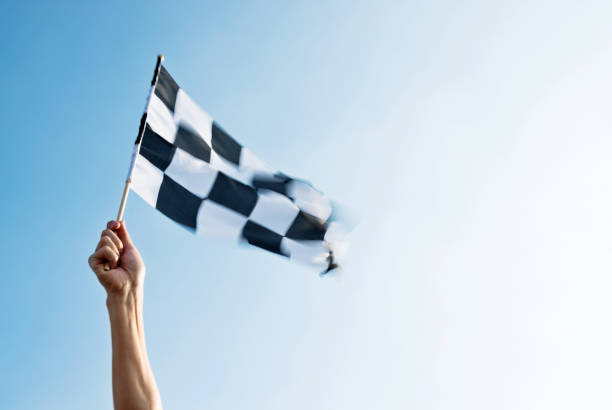 человек стороны проведения клетчатый флаг на ветру - checkered flag flag auto racing starting line стоковые фото и изображения