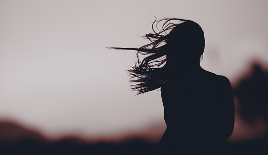 rear view of woman silhouette with her flying hair thinking away and enjoying the silence.
