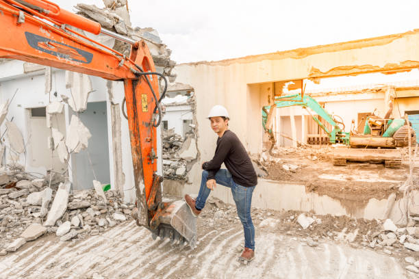 istock Asian man standing with Backhoe Robot Equipment on construction zone. There is a piece of cement around. 811827548