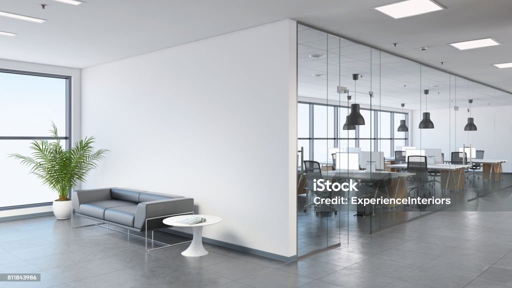 Modern business office space with lobby Interior view of a modern office, business template. Left side of the picture is large sofa with a plant and coffee table. Blank wall for copy space. On the right, many office desks with pendant lights above. large windows. gray floor tiles, white walls. Render Office Stock Photo