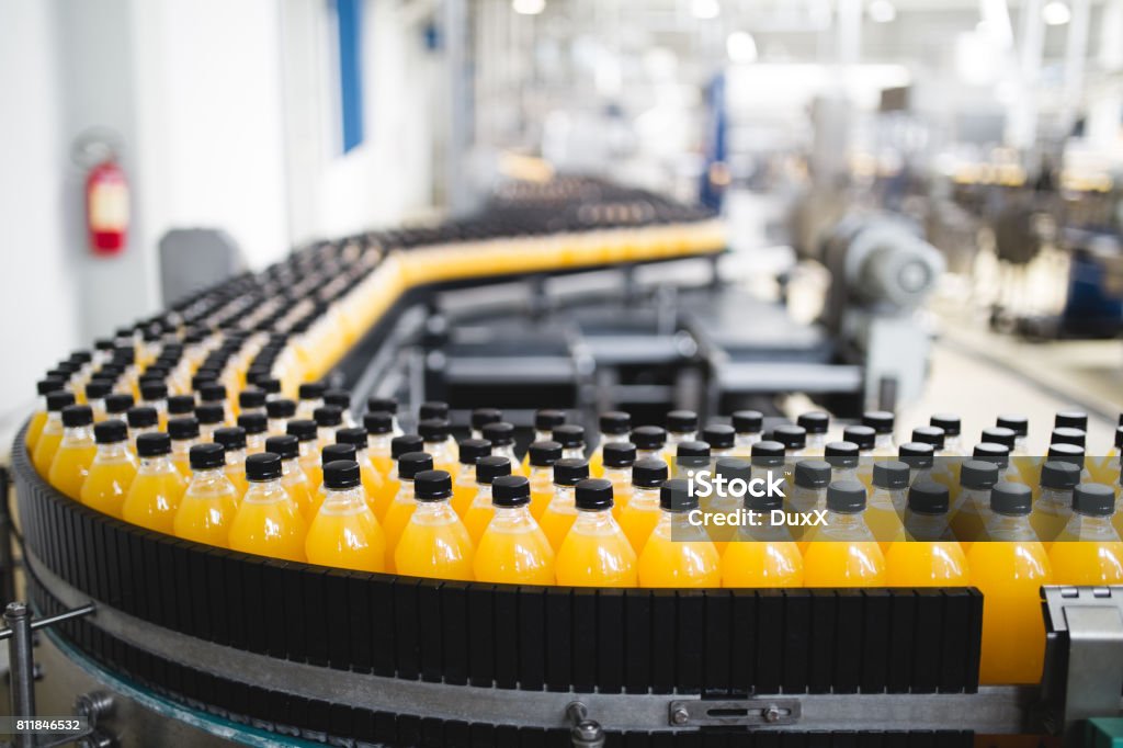 Industrial indoors and machinery Industrial factory indoors and machinery. Robotic factory line for processing and bottling of soda and orange juice bottles. Selective focus. Short depth of field. Factory Stock Photo