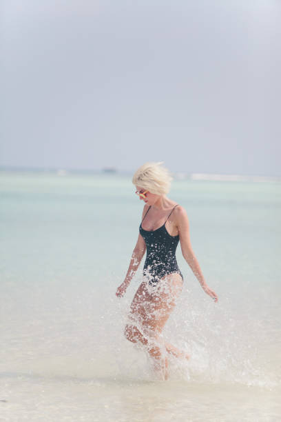 istock Woman in bikini running through water on sandy beach, Maldives 811849334