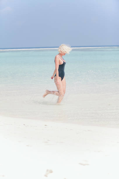 istock Woman in bikini running through water on sandy beach, Maldives 811849700